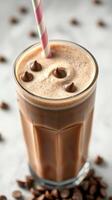 Chocolate milkshake topped with chocolate chips and a striped straw in a glass on a marble surface photo