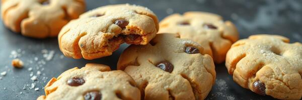 Freshly baked chocolate chip cookies cooling on a black surface with a crumbly bite taken out photo