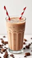 Creamy chocolate beverage served in a tall glass with red and white striped straws on a light background photo