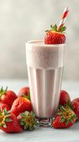 Delicious strawberry milkshake served in a tall glass garnished with fresh strawberries and striped straw photo