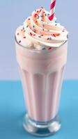 Delicious milkshake topped with whipped cream and colorful sprinkles on a blue background photo