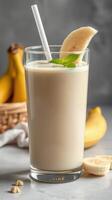 Refreshing banana smoothie served in a clear glass with fresh fruit on a kitchen countertop photo