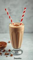 Creamy chocolate smoothie served in a tall glass with two striped straws photo