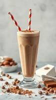 Creamy chocolate drink served in a tall glass with red and white straws and garnished with cocoa powder photo