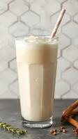 Creamy milkshake served in a tall glass with a straw against a patterned background photo