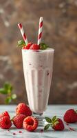 Refreshing raspberry milkshake topped with mint leaves and berries served in a tall glass photo