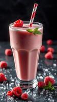 Refreshing raspberry smoothie served in a tall glass with mint leaves and striped straw photo