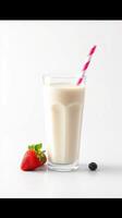 Fresh strawberry smoothie served in a clear glass with a pink striped straw beside vibrant berries on a white background photo
