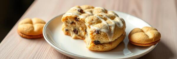 Freshly baked cookies served on a plate with drizzled icing and bite taken out of one photo