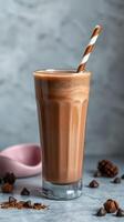 Delicious chocolate smoothie in a tall glass with a straw served on a textured gray background photo