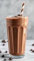 Delicious chocolate milkshake topped with whipped cream and a straw served on a marble surface photo