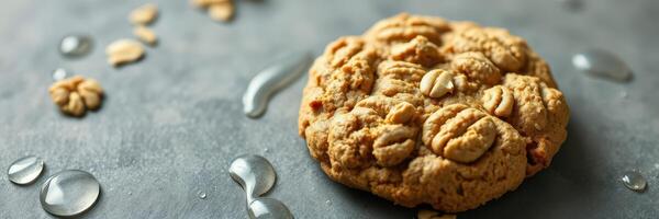 Freshly baked oatmeal cookie with water droplets on a dark surface photo