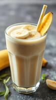 Creamy banana smoothie served in a tall glass with fresh banana slices and a striped straw on a marble countertop photo