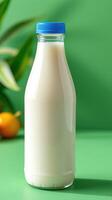 Fresh milk in a clear bottle on a colorful background with green plants and orange fruit photo