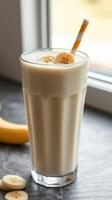 Refreshing banana smoothie served in a tall glass with a striped straw on a kitchen counter photo