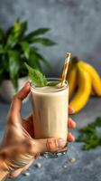 Refreshing banana mint smoothie served in a clear glass with a striped straw on a kitchen countertop photo