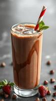 Chocolate milkshake with fresh strawberries and striped straw served in a tall glass on a marble countertop photo