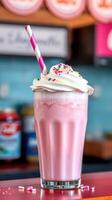 Bright pink milkshake topped with whipped cream and colorful sprinkles at a diner photo