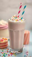 Delicious milkshake topped with whipped cream and colorful sprinkles served in a tall glass with straws photo