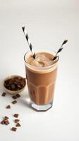 Creamy chocolate chilled beverage with stripes in glass and chocolate pieces on a table photo