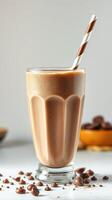 Delicious chocolate milkshake in a tall glass with a striped straw on a white background with chocolate chips photo