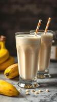 Refreshing banana smoothies served in tall glasses with striped straws and fresh bananas nearby photo