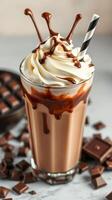 Creamy chocolate milkshake topped with whipped cream and drizzle served with chocolate pieces photo