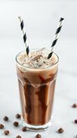 Refreshing chocolate drink served in a tall glass with ice cubes and striped straws on a marble table photo