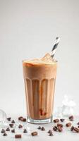 Creamy chocolate beverage with ice cubes and chocolate chips on a light background photo