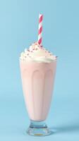 Creamy strawberry milkshake in a glass with a striped straw against a light blue background photo