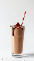 Chocolate milkshake with a red and white striped straw drips deliciously in a clear glass photo