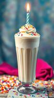 Delicious milkshake with whipped cream and colorful sprinkles topped with a candle photo