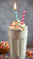 Creamy milkshake topped with whipped cream, colorful sprinkles, and birthday candles in a stylish glass photo