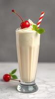 Creamy milkshake topped with whipped cream and cherries in a glass on a marble countertop in a cozy setting photo