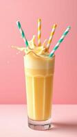 Refreshing fruit smoothie in a tall glass with colorful straws against a pink background photo