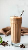 Creamy chocolate milkshake topped with whipped cream and a striped straw served in a tall glass photo