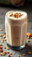Creamy nut-based beverage garnished with seeds served in a tall glass on a dark surface photo
