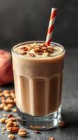 Creamy smoothie topped with crunchy granola and a striped straw in a glass on a dark surface photo