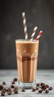 Delicious chocolate milkshake topped with striped straws served in a tall glass with coffee beans scattered around photo