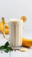 Creamy banana smoothie garnished with banana slice and mint leaves on a light background photo