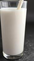 Creamy beverage served in a tall glass with a straw against a dark background photo