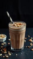 Delicious chocolate almond smoothie served in a tall glass with crushed nuts on top and scattered almonds around photo
