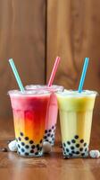 Colorful bubble tea drinks in clear cups on a wooden table with colorful layers and tapioca pearls photo