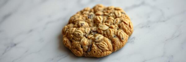 Homemade oatmeal cookie with chocolate chips on marble countertop in a bright kitchen photo