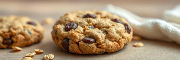 Chocolate chip oat cookies on wooden table with scattered oats and a white cloth photo