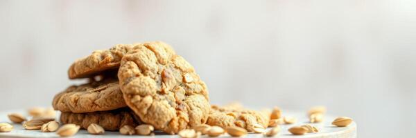 Oatmeal cookies stacked on a white surface with oats scattered around during a cozy kitchen setting photo