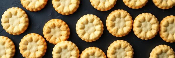 Delicate golden cookies arranged neatly on a dark surface for a delightful culinary experience photo