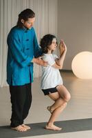 A yoga instructor in training helps a child to do exercises in the gym photo