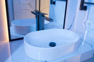 Chrome water faucet and white pedestal sink in bathroom . Stylish bathroom photo