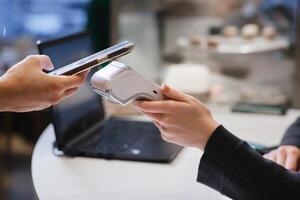A customer uses his phone to pay through a terminal . Concept of cashless technologies and money transfers photo